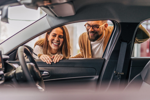 A couple looking inside a new car at the dealership